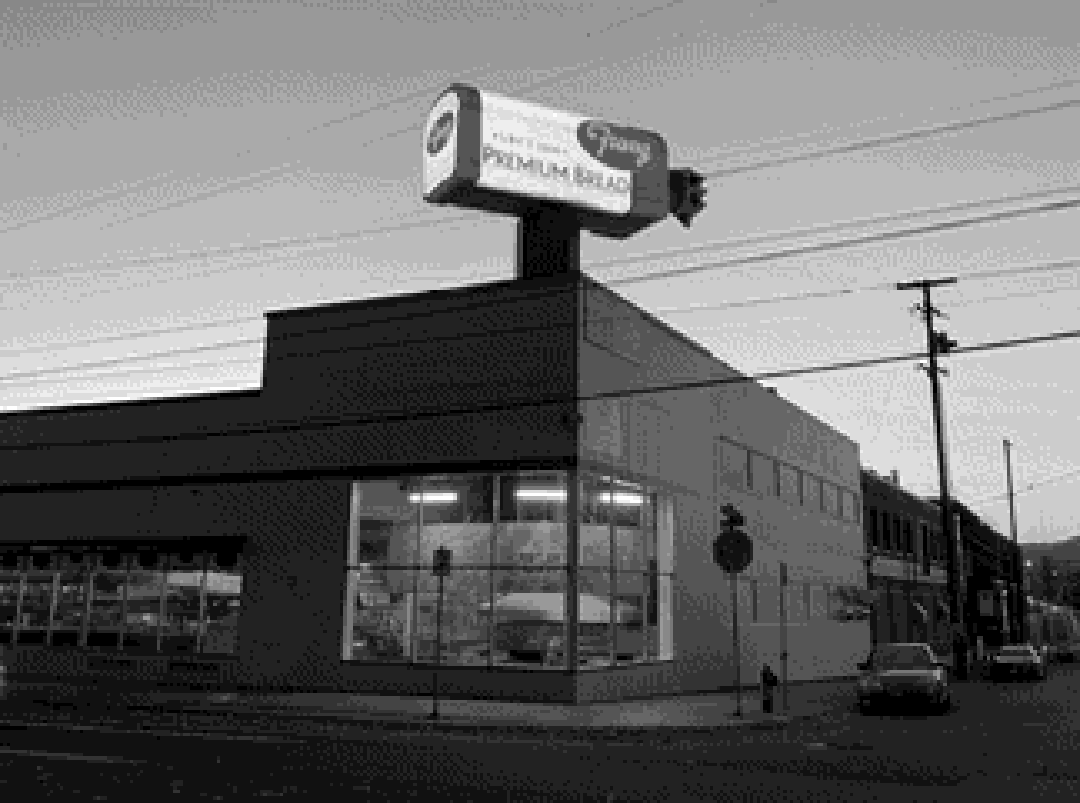 The giant rotating bread loaf sign atop a bakery building in Portland, photographed at dusk.